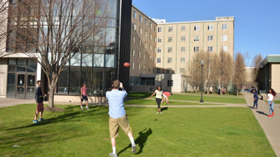 Students tossing a football in front of Canisius residence halls.